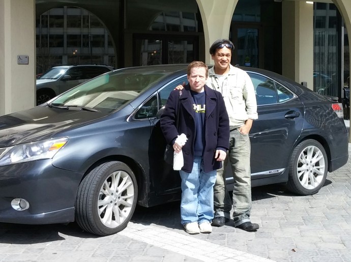 Joel and I pose in front of the karaoke-equipped Lexus that he drives for Uber.